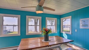 A room with teal walls, a wooden table, and a ceiling fan. - Lakefront Cottage w/ Fishing & Private Yard! (Port Clinton)