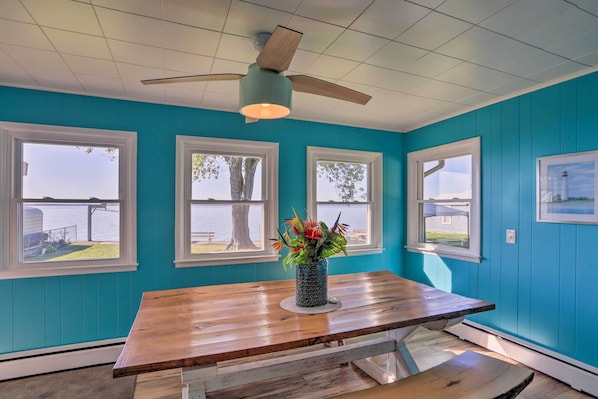 A room with teal walls, a wooden table, and a ceiling fan.
