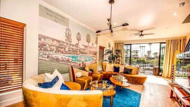 A modern living room with a large mural, comfortable seating, and a view of the outdoors.