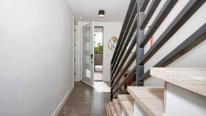 A modern interior with a staircase, a hallway, and a door leading to another room.