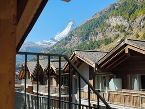 A mountain lodge with wooden cabins, a balcony, and a view of snow-capped mountains. - Peaky Riders Self Check-in Hotel (Zermatt)