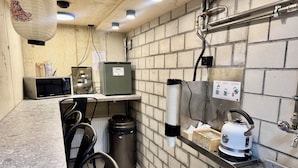 A compact kitchen with a microwave, a small refrigerator, a kettle, and a sink.