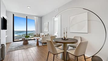 Uma sala de estar moderna com uma janela grande, uma mesa de jantar redonda e um sofá.