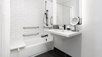 Un baño moderno con una bañera blanca, ducha, tocador con espejo y un inodoro.