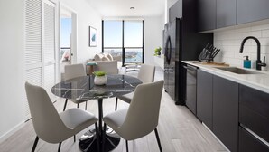 A modern kitchen with a black refrigerator, white cabinets, and a large window offering a city view. - The Elser Hotel Miami (Miami)