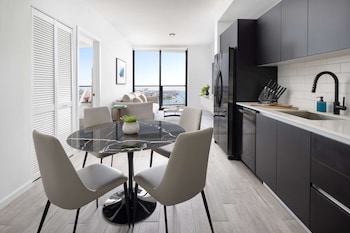 A modern kitchen with stainless steel appliances, white tiles, and a view of the city through the window. at The Elser Hotel Miami