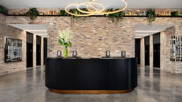A reception area with a brick wall, a black reception desk, and a modern light fixture.