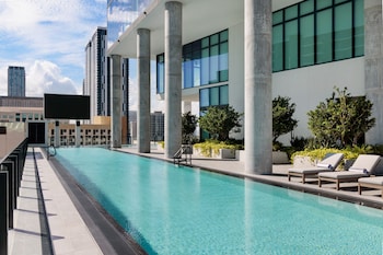A modern building with a glass facade, white structural elements, and palm trees in the foreground. at The Elser Hotel Miami