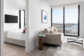 A modern living room with a sofa, a coffee table with a plant, and a view of the kitchen in the background. at The Elser Hotel Miami
