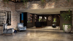 A spacious lobby with a brick wall, a reception desk, and a seating area with a sofa and armchairs. - The Elser Hotel Miami (Miami)