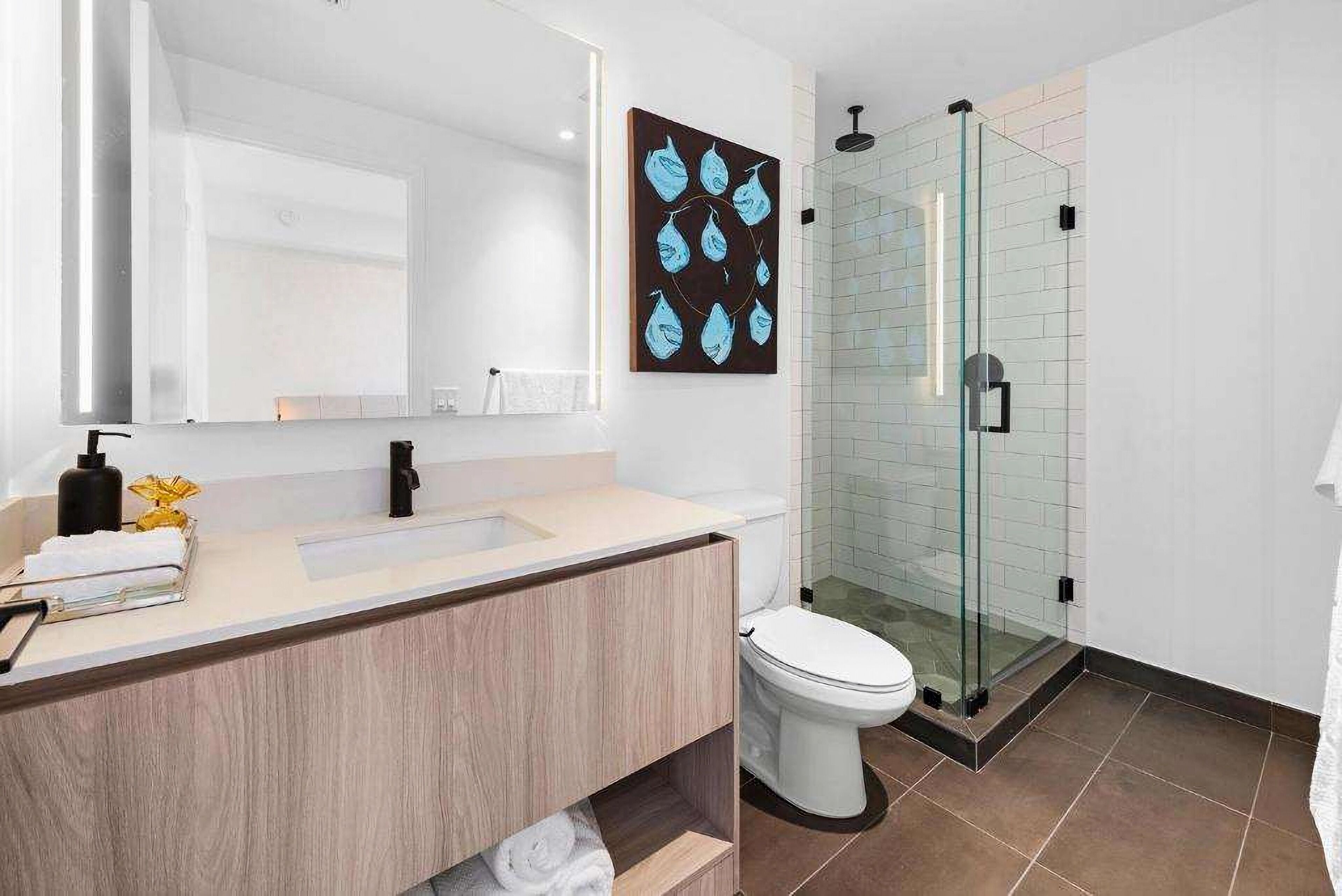A modern bathroom with a glass shower enclosure, a white toilet, and a wooden vanity with a sink.