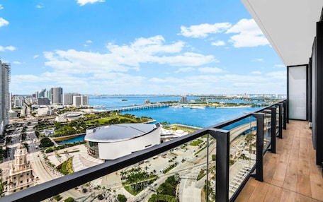 A balcony with a view of a cityscape, including a large stadium, a bridge, and a body of water.
