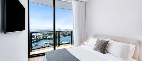 Une chambre d’hôtel moderne dotée d’un grand lit, d’une télévision à écran plat et d’un balcon offrant une vue sur la ville.