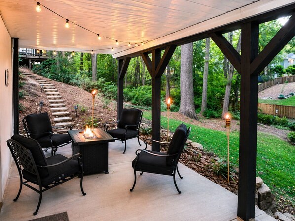 Un patio al aire libre con una chimenea, dos sillas y una mesa.
