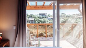 Een slaapkamer met een grote glazen schuifdeur die leidt naar een balkon met een houten balustrade.