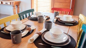 Een eettafel gedekt met borden, kommen en kopjes, omringd door stoelen.