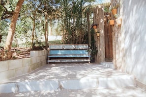 Un banco de madera de diseño rústico, ubicado en un jardín con escalones de piedra y plantas en macetas.
