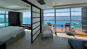 Ein modernes Hotelzimmer mit einem großen Bett, einer Sitzecke mit Meerblick und einem Balkon mit Holzboden.