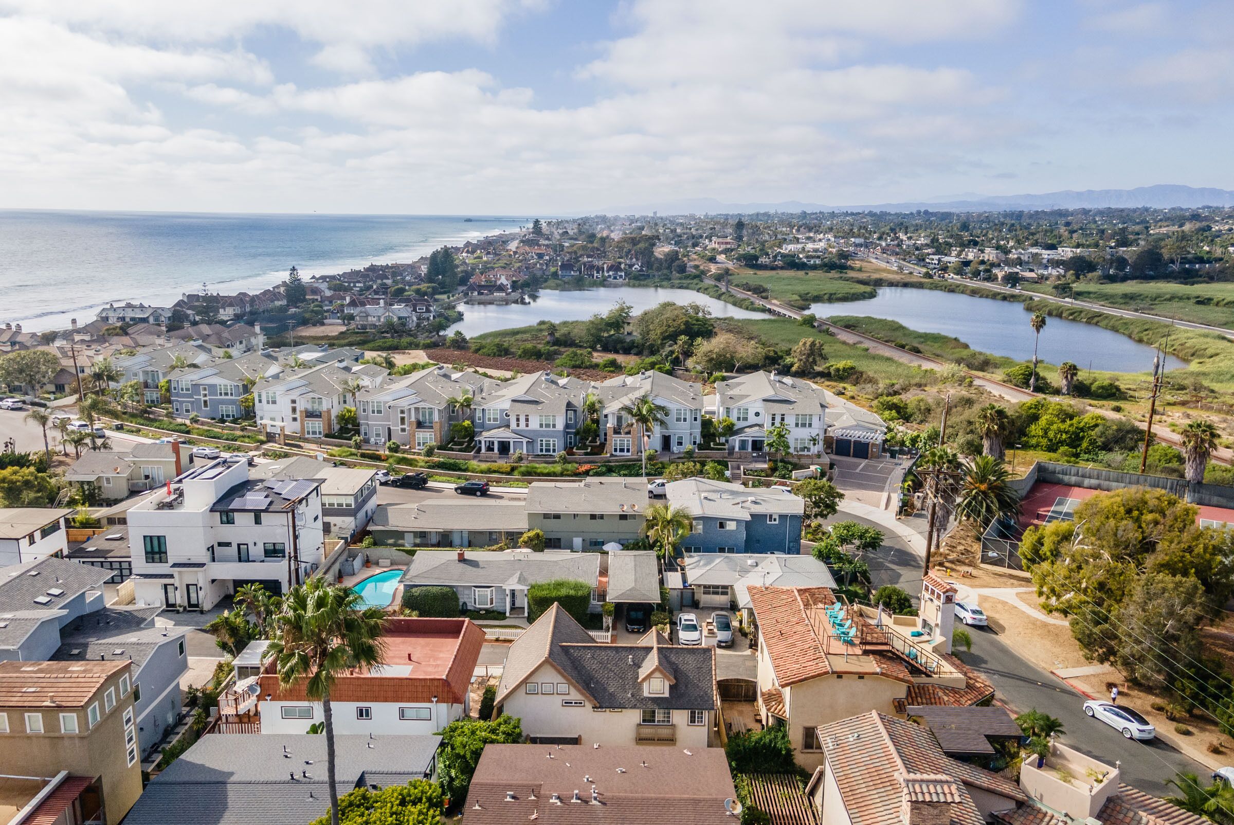 A residential area with houses, a swimming pool, and a view of the ocean.