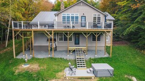 A two-story house with a deck, a covered outdoor seating area, and a staircase leading to the deck.