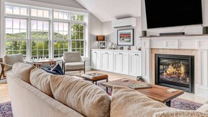 A living room with a fireplace, television, and large windows.
