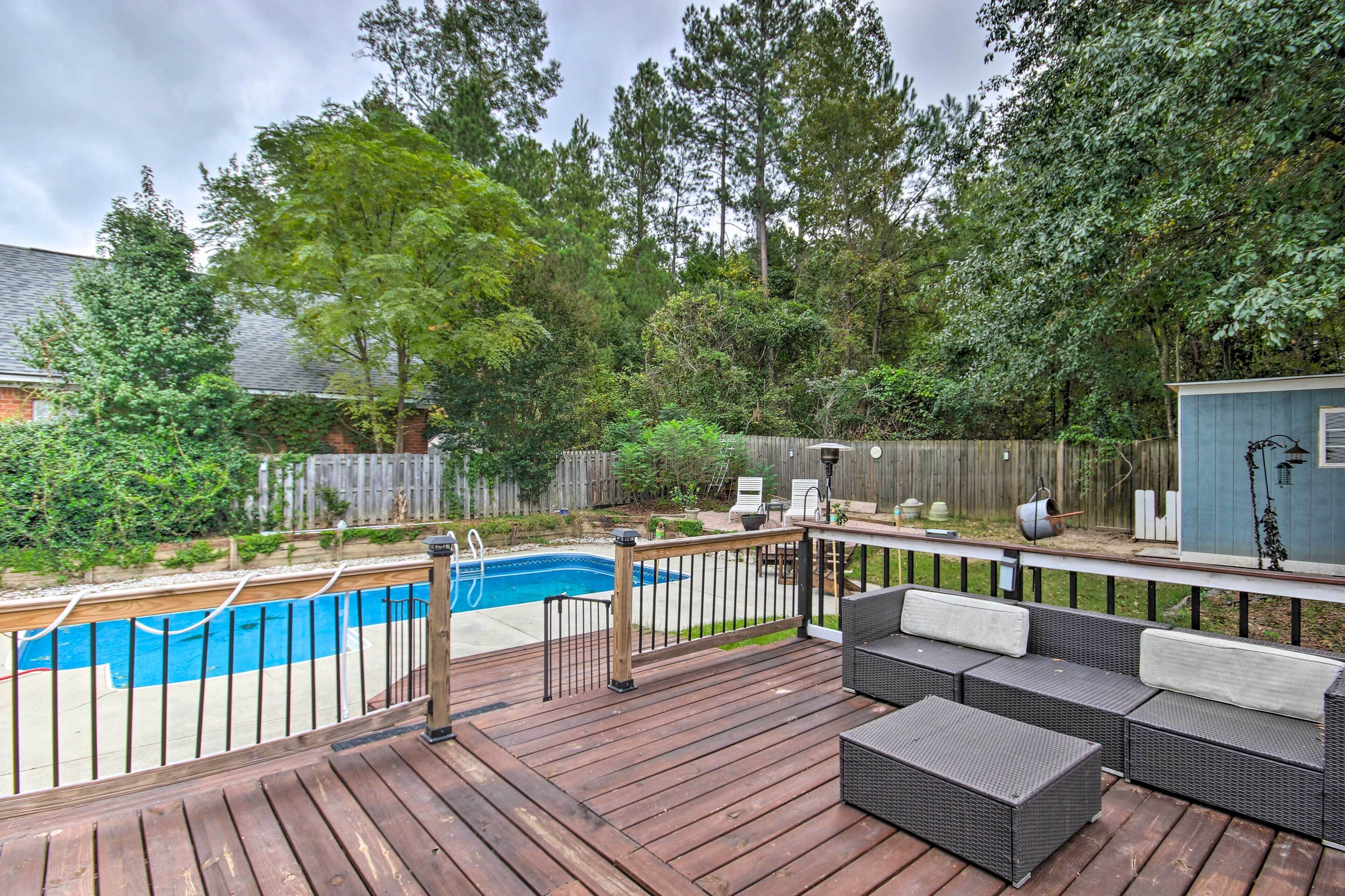 A wooden deck with a pool, outdoor furniture, and a wooden fence.