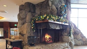 Een stenen open haard met een kerstboom en decoraties, een vlammend vuur en een rode kerstdoos van de Kerstman.