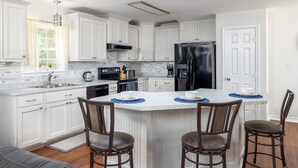 Una cocina moderna con armarios blancos, un refrigerador negro y una isla central con taburetes de bar.