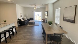 A spacious living area with a dining table, chairs, and a sofa. - Beautiful new home with lake view near hiking trails (Oak Ridge)