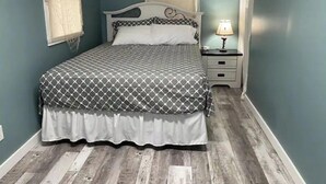 Un dormitorio con cama, mesita de noche y lámpara.