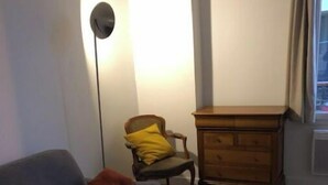 Un salon avec un canapé, une petite table, un meuble en bois et une chaise agrémentée d’un coussin jaune.