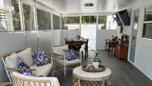 Un espacio de estar al aire libre con techo, con muebles de mimbre, una mesa y sillas.