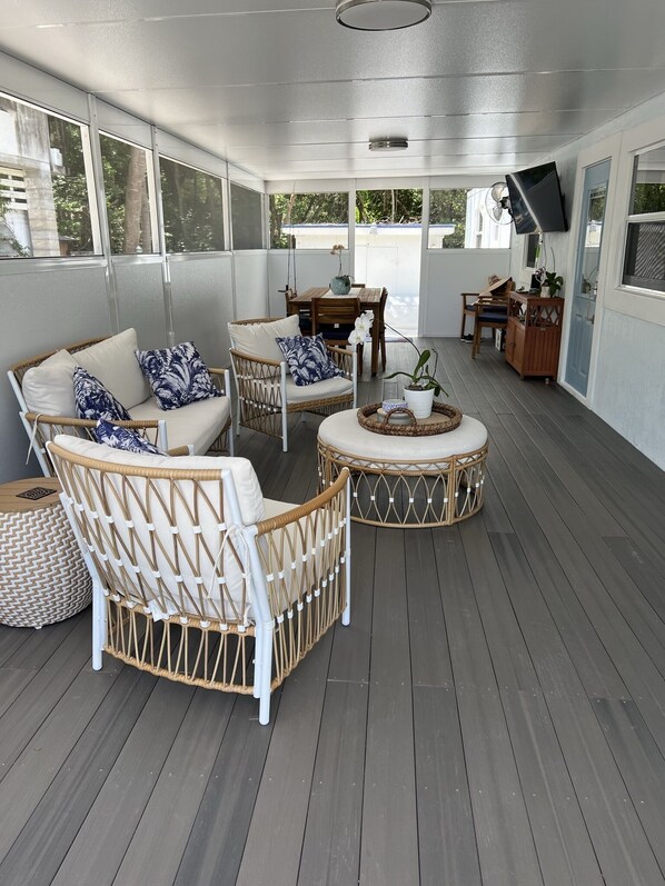 A covered outdoor seating area with wicker furniture, a table, and chairs. - Stress Free Home W/Boat Ramp and Private Beach (Key Largo)