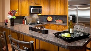 Une cuisine dotée de meubles en bois, d’un réfrigérateur en acier inoxydable, d’un four à micro-ondes et d’un plan de travail en granit.