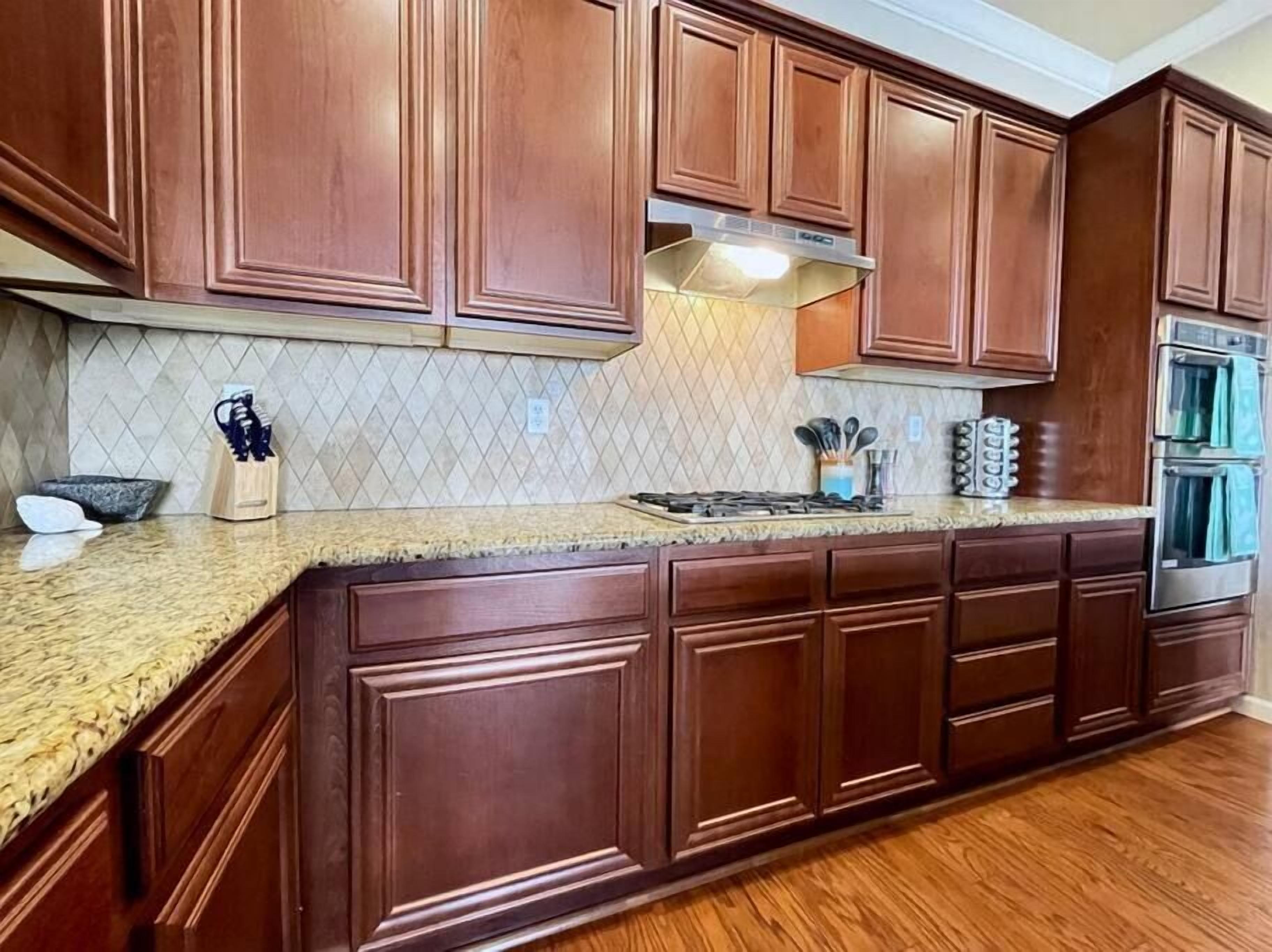 A kitchen with wooden cabinets, a granite countertop, and stainless steel appliances.