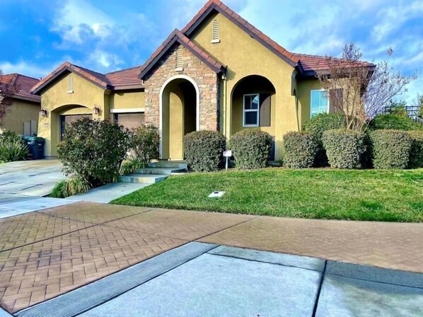 A residential building with a brick facade, a central arched entrance, and a well-maintained lawn.