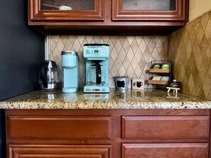 A kitchen with a coffee maker, a kettle, and a coffee mug on the counter.