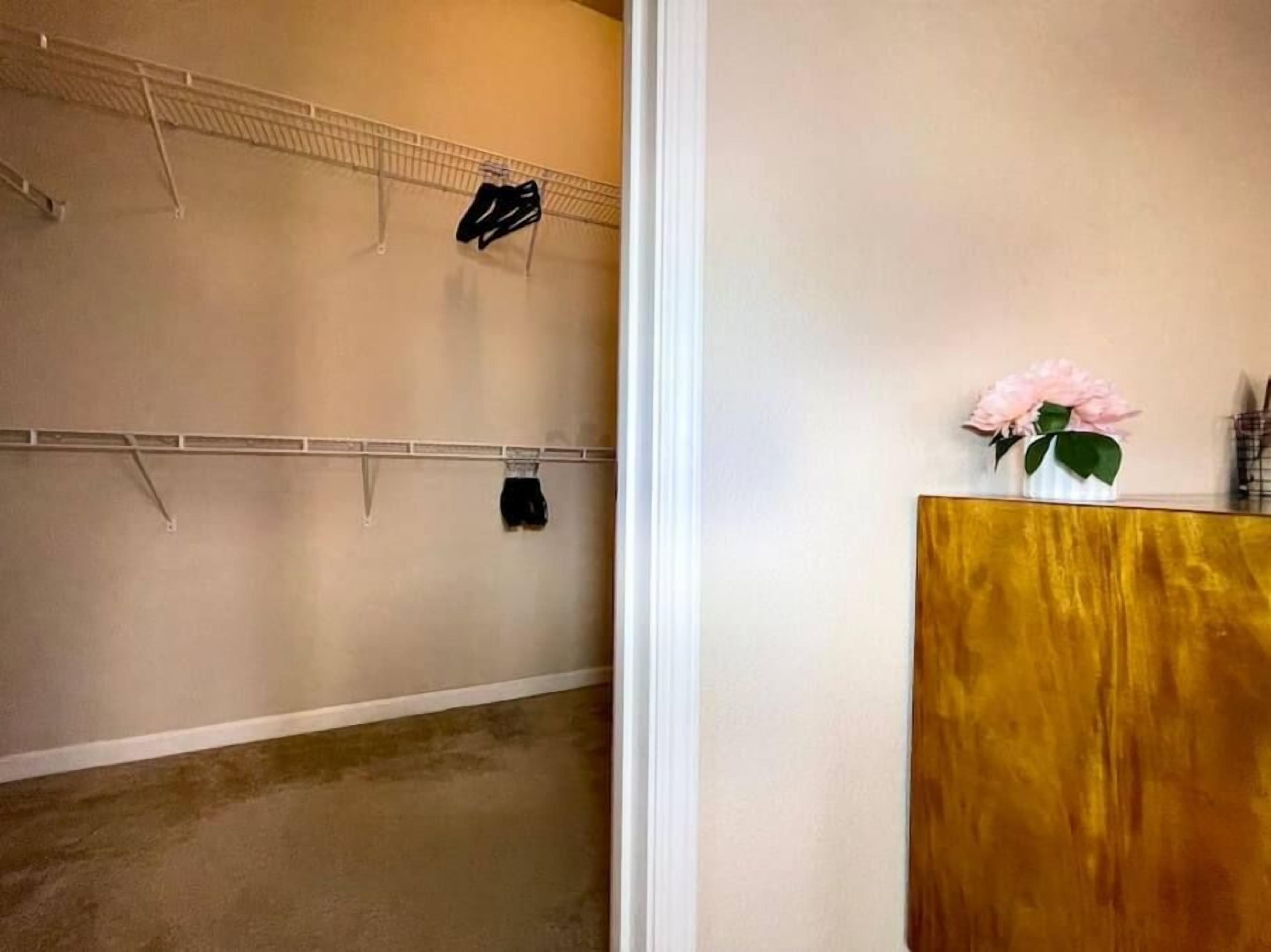 Una habitación con un armario de madera, un zapatero en la pared y un jarrón con flores.