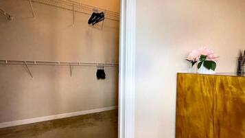 Una habitación con un armario de madera, un zapatero en la pared y un jarrón con flores.