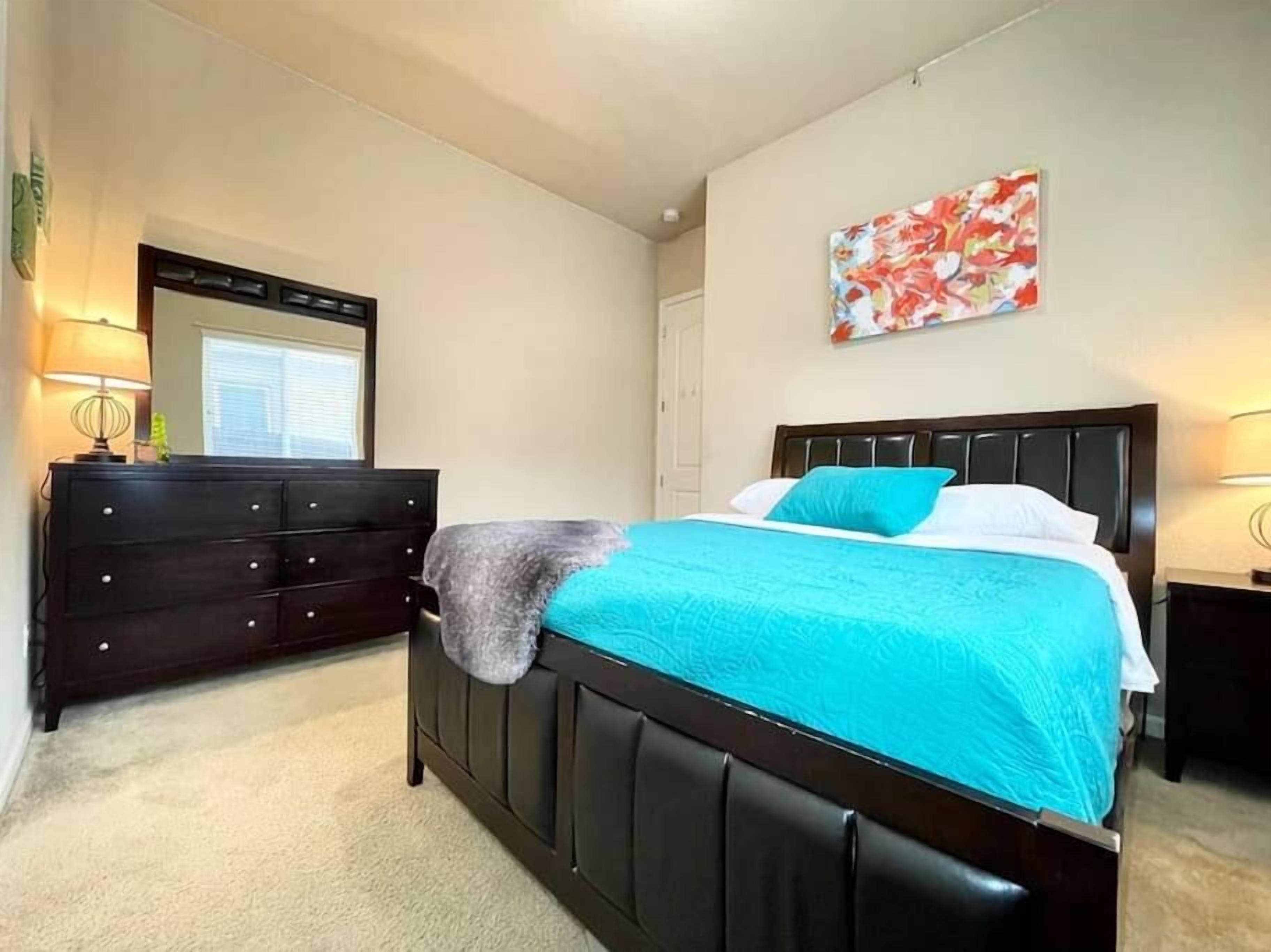 Une chambre à coucher avec un lit, une commode et des œuvres d’art accrochées au mur.