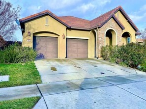 A two-story house with a garage, a driveway, and a well-maintained lawn.