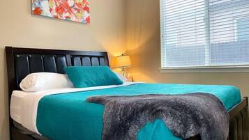 A bed with a headboard, a pillow, a blanket, and a wall-mounted lamp.