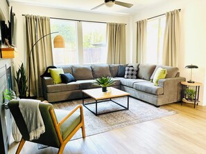 A living room with a sectional sofa, a coffee table, a floor lamp, and a side table with a plant. - Remodeled 4BR near Historic Folsom · Walk to Shops · Pets OK (Folsom)
