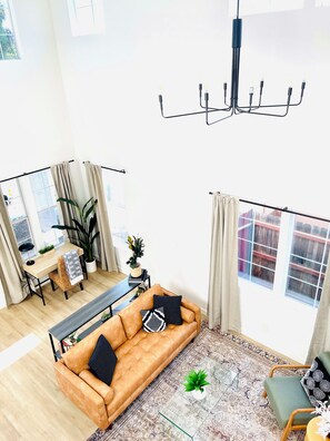 Een moderne woonkamer met een bank, een salontafel, een eethoek en een groot raam.