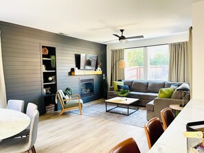 A modern living room with a fireplace, sofa, and dining area.