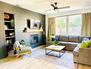 A living room with a fireplace, sofa, coffee table, and a bookshelf.