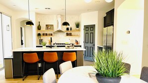 A modern kitchen with a central island, bar stools, and pendant lighting.