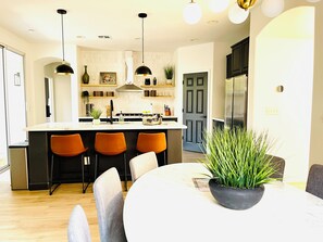 Une cuisine moderne dotée d’un îlot central, de sièges de bar et de luminaires suspendus.