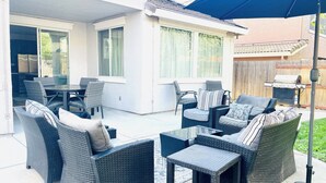 An outdoor patio with wicker furniture, a grill, and a covered area.