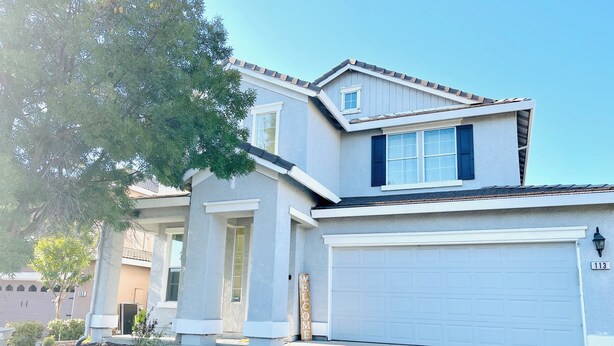A two-story house with a garage, a front porch with steps, and a mailbox.